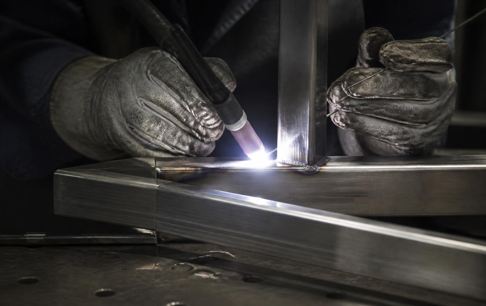 Welder TIG welding a stainless steel frame in the fabrication bay